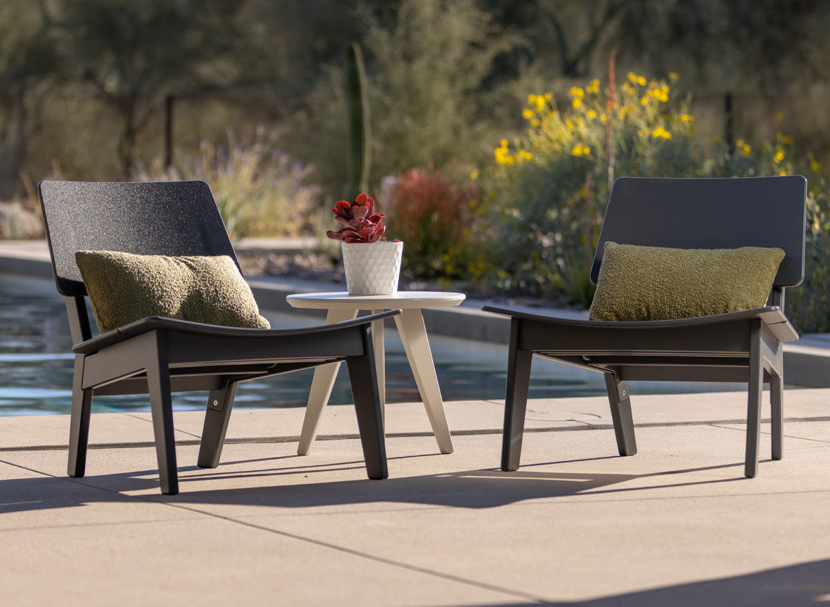 a pair of lago lounge chairs with a satellite side table near a pool.