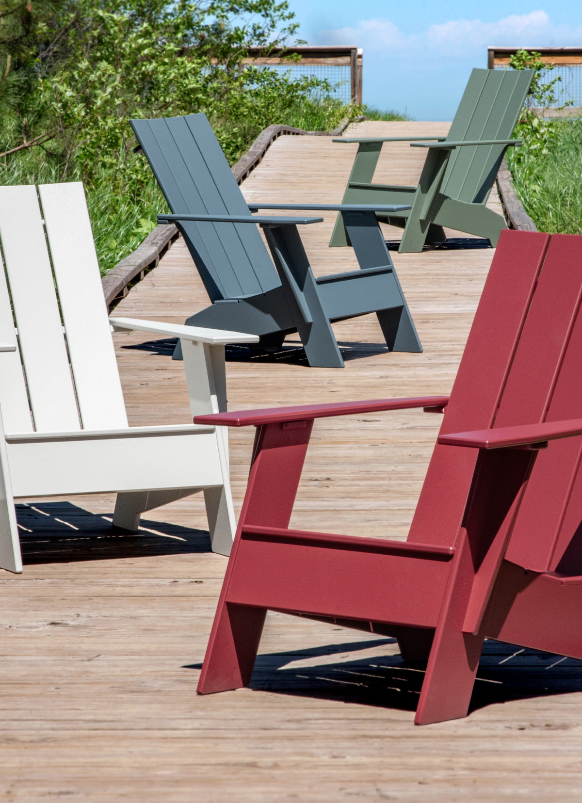 Four Adirondacks arranged on a deck. From front to back, Chili, Fog, Ash Blue, Sage.