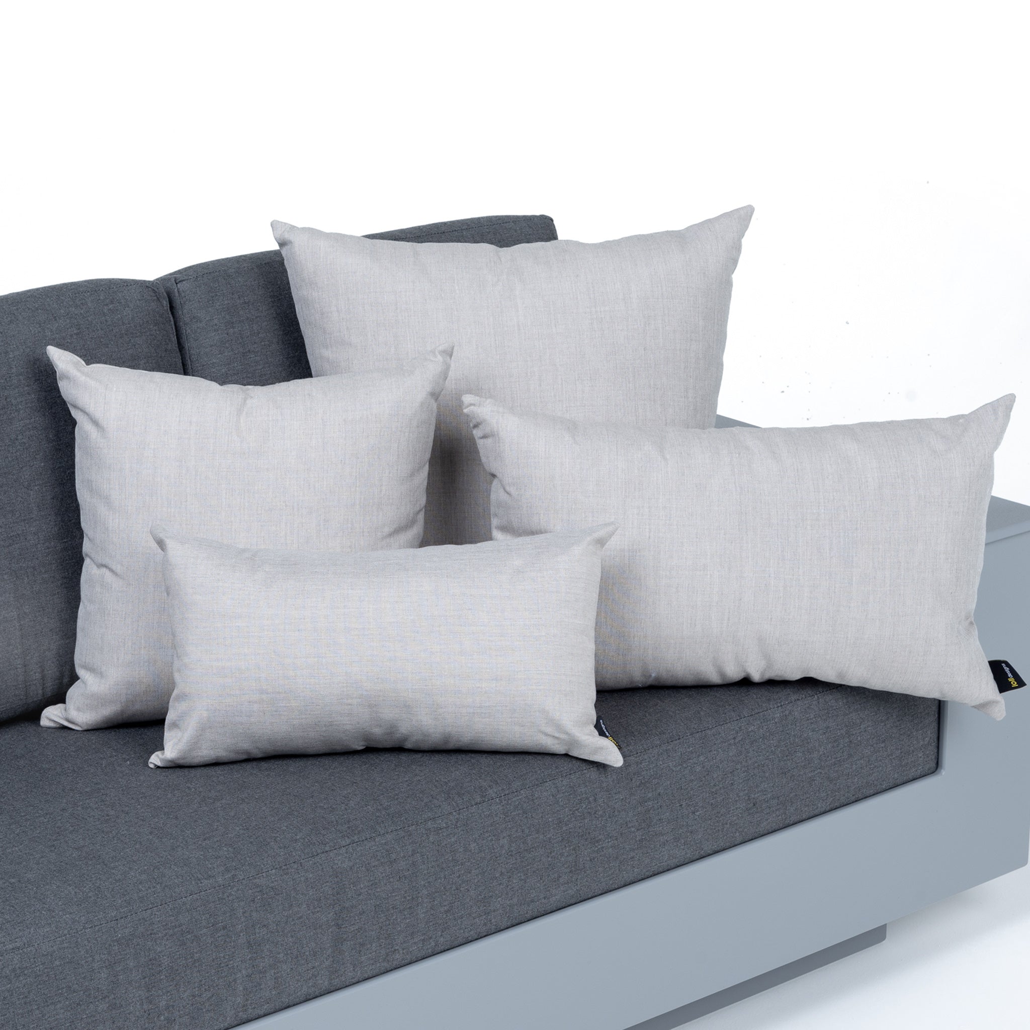 studio image of small square, large square, small rectangle, and large rectangle pillows in flax on a nisswa sofa with charcoal cushions.