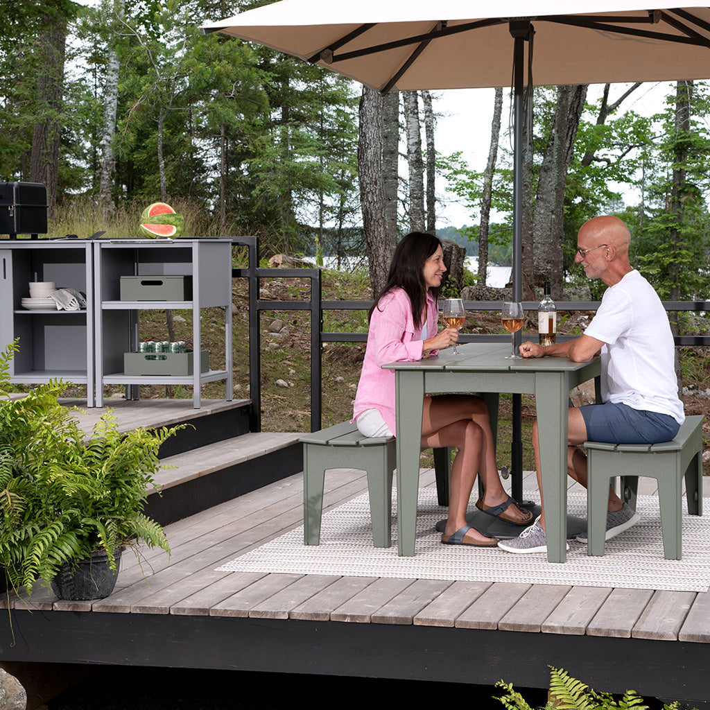 A man and woman sitting at a sage Alfresco 72 Dining Set on a deck with an A La Carte Set.