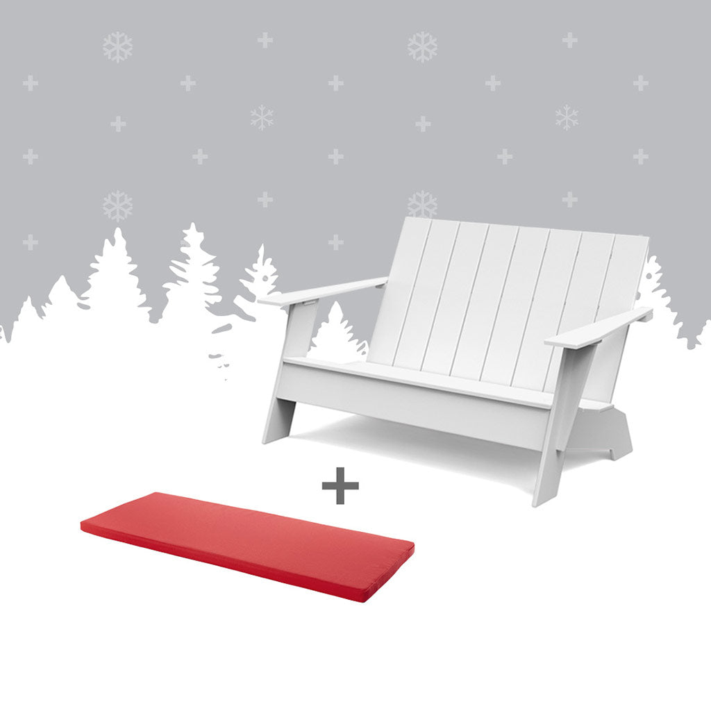 White adirondacak bench and a red bench cushion against grey forest background.