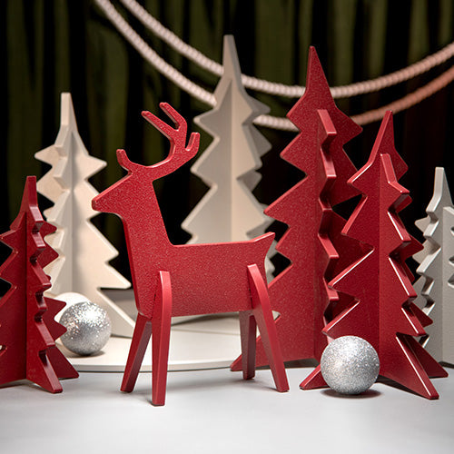 Red deer and tree-shaped ornaments with silver ornaments on a white surface.