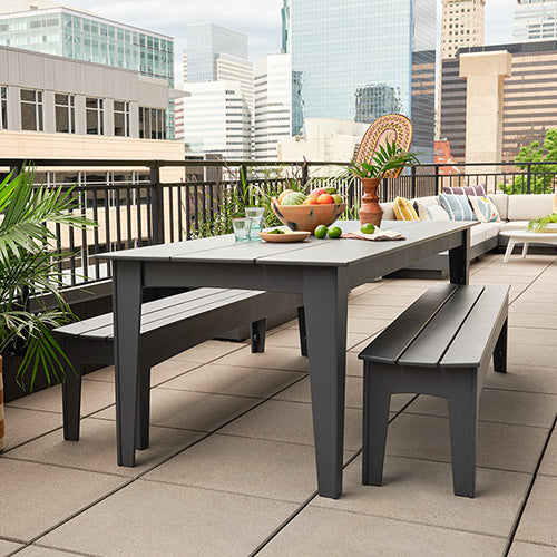 Outdoor patio set with table, benches, and city skyline in the background