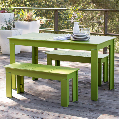 leaf green lollygagger picnic table and 2 benches on wooden deck with a wooded background.
