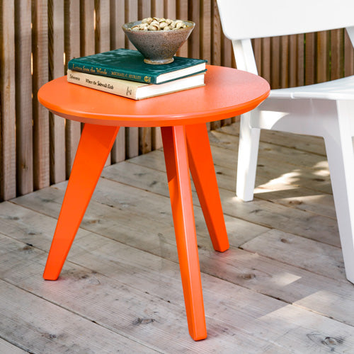 sunset orange, satellite table next to lago chair on wooden deck. 2 books and bowl are sat on top of the table.